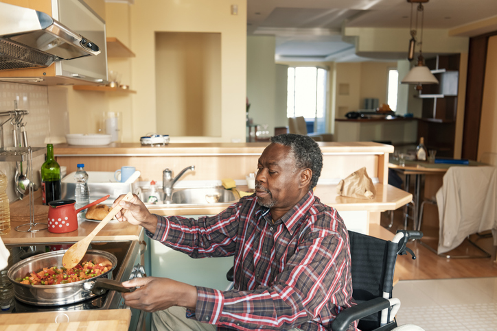 mężczyzna na wózku inwalidzkim przygotowuje obiad w domu