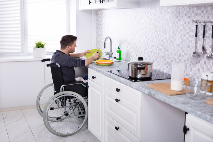 mężczyzna na wózku zmywa naczynia