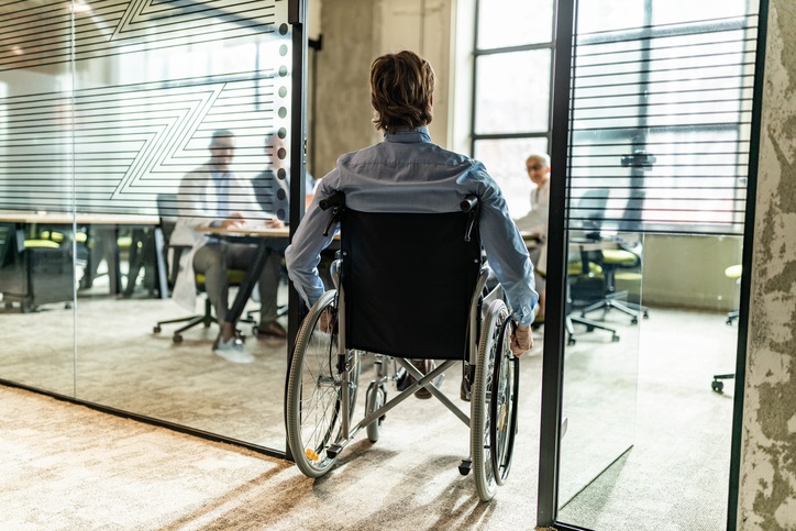 osoba na wózku inwalidzkim wjeżdża do pokoju biurowego